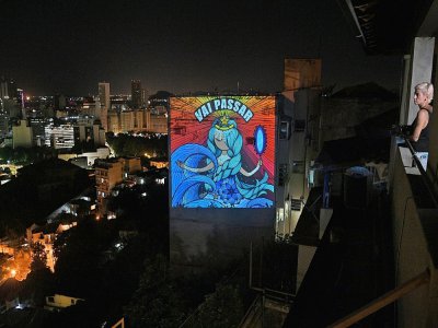 A Rio, l'artiste brésilienne Rafamon, confinée volontairement, projette sur un écran géant son oeuvre qui dit: "Ca va passer", le 23 mars 2020 - Carl DE SOUZA [AFP]