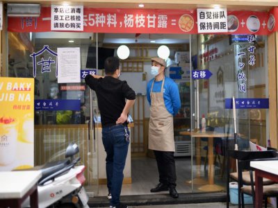 Des employés d'un restaurant munis de masques de protection contre le coronavirus attendent le client à Huanggang, dans la province chinoise du Hubei, le 26 mars 2020 - Noel Celis [AFP]