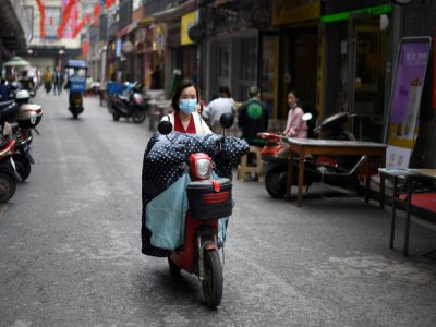 Une femme à moto, le visage couvert d'un masque de protection, dans une rue de Huanggang, dans la province chinoise du Hubei, le 26 mars 2020 - Noel Celis [AFP]