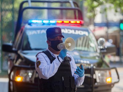 Un policier utilise un haut-parleur pour inviter les passants à rentrer chez eux, le 25 mars 2020 à Monterrey, au Mexique - Julio Cesar AGUILAR [AFP]