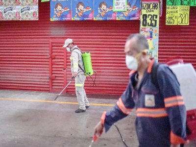 Des employés désinfectent un marché alimentaire pour lutter contre l'épidémie de coronavirus, le 24 mars 2020 à Mexico - PEDRO PARDO [AFP]