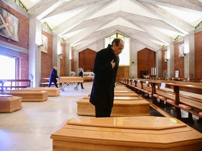 Le prêtre de la paroisse de Seriate, Don Mario, s'incline devant l'un des cercueils entreprosés dans l'église de sa commune, située près de Bergame, dans le nord de l'Italie, le 26 mars 2020 - Piero CRUCIATTI [AFP]