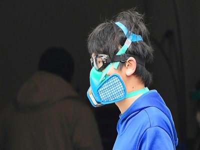 Un piéton porte un masque de protection et des lunettes de piscine le 24 mars à Monterey Park, en Californie - Frederic J. BROWN [AFP]