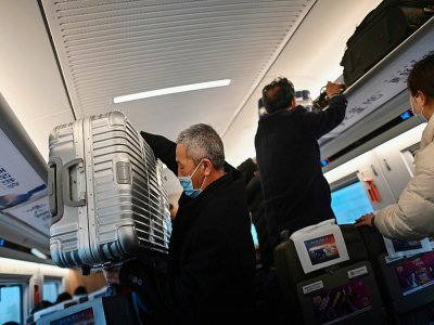 Des voyageurs portant des masques de protection contre le coronavirus montent dans un train à destination de Wuhan, le 28 mars 2020 à Shanghai - Hector RETAMAL [AFP]