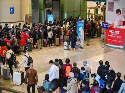 Des voyageurs font la queue pour passer au contrôle de leur température et de leur identité à leur arrivée à la gare de Wuhan, dans la province chinoise du Hubei, le 28 mars 2020 - HECTOR RETAMAL [AFP]