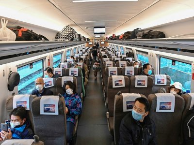 Des voyageurs portant un masque de protection contre le coronavirus dans un train à destination de Wuhan, le 28 mars 2020 - Hector RETAMAL [AFP]