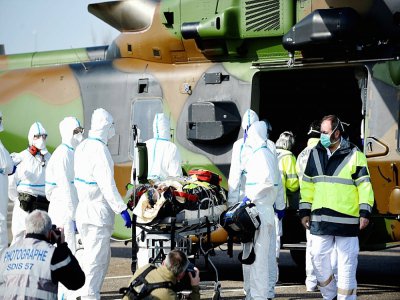 Des équipes médicales transportent un patient contaminé par le Covid-19 pour l'évacuer à bord d'un hélicoptère vers l'hôpital d'Essen, en Allemagne, le 28 mars 2020 sur un parking près du CHR de Metz - JEAN-CHRISTOPHE VERHAEGEN [AFP]