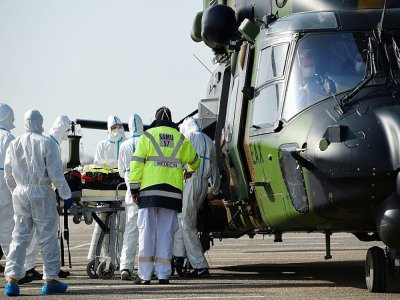 Des équipes médicales transportent un patient contaminé par le Covid-19 pour l'évacuer à bord d'un hélicoptère vers l'hôpital d'Essen, en Allemagne, le 28 mars 2020 sur un parking près du CHR de Metz - JEAN-CHRISTOPHE VERHAEGEN [AFP]
