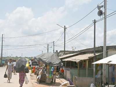 Des habitants font leurs courses dans une rue du village d'Azaguié Ahoua, près d'Abidjan, où des hauts-parleurs diffusent des messages sur le coronavirus, le 27 mars 2020 en Côte d'Ivoire - ISSOUF SANOGO [AFP]