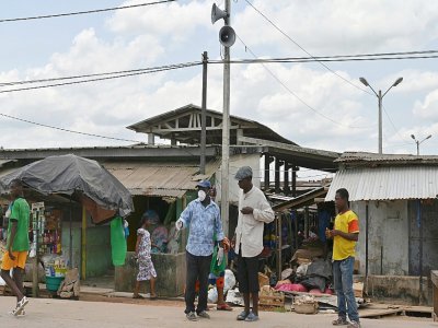 Des habitants dans une rue du village d'Azaguié Ahoua, près d'Abidjan, où des hauts-parleurs diffusent des messages sur le coronavirus, le 27 mars 2020 en Côte d'Ivoire - ISSOUF SANOGO [AFP]
