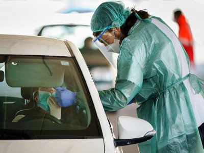 Une soignante en combinaison de protection teste un automobiliste, le 28 mars 2020 à Burgos en Espagne - CESAR MANSO [AFP]