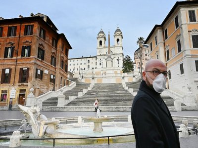 Un homme qui porte un masque contre le coronavirus marche près de la Place d'Espagne déserte à Rome le 12 mars 2020 - Alberto PIZZOLI [AFP]
