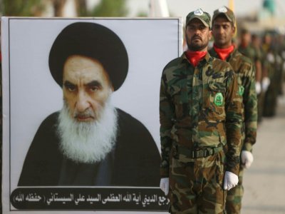 Des membres d'une force paramilitaire chiite au garde à vous devant le portrait de l'ayatollah Ali Sistani, le 30 août 2019 à Kerbala, en Irak - Mohammed SAWAF [AFP/Archives]
