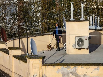 Un homme promène son chien sur le toit de son immeuble, à Rome le 30 mars 2020 - Laurent EMMANUEL [AFP]