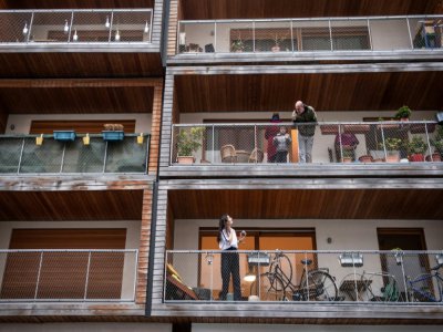 des Parisiens, voisins, se parlent de balcon à balcon à Paris le 20 mars 2020. - Martin BUREAU [AFP]