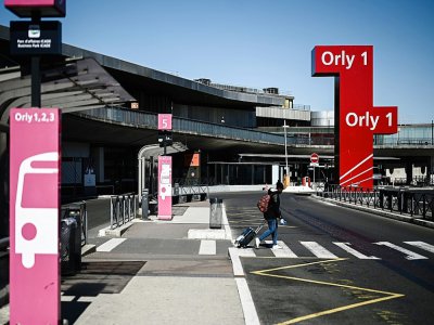 Une personne sort du terminal 1 de l'aéroport d'Orly, désert, le 30 mars 2020, à la veille de sa fermeture en raison de l'effondrement du trafic aérien pendant la pandémie du nouveau coronavirus - Philippe LOPEZ [AFP]