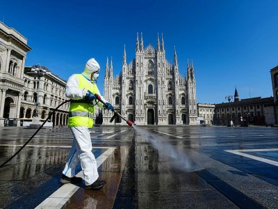 Un employé des services de l'environnement vaporise des produits désinfectants  Piazza Duomo à Milan, le 31 mars 2020 - Piero Cruciatti [AFP]