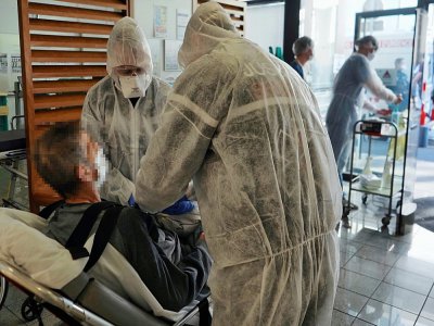 Des soignants accueillent un patient contaminé par le Covid-19 à son arrivée dans une unité de soins intensifs à l'hôpital universitaire de Tours, le 31 mars 2020 - GUILLAUME SOUVANT [AFP]