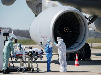 Du personnel médical évacue un patient contaminé par le Covid-19 à bord d'un Airbus A330 de l'armée de l'air, le 31 mars 2020 à l'aéroport de Bâle-Mulhouse dans le cadre de l'opération Morphée - SEBASTIEN BOZON [AFP]