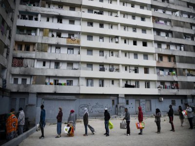Des habitants du quartier Maison Blanche (Marseille) attendent la distribution de nourriture, le 31 mars 2020 au pied de leur immeuble - Anne-Christine POUJOULAT [AFP]