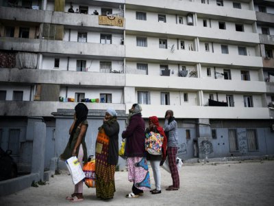 Des habitants du quartier Maison Blanche (Marseille) attendent la distribution de nourriture le 31 mars 2020 devant leurs immeubles - Anne-Christine POUJOULAT [AFP]