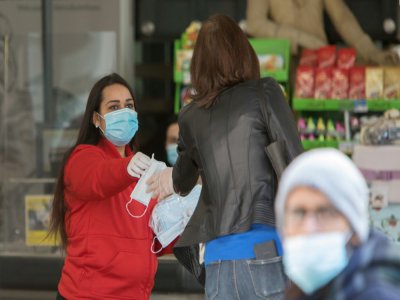 Une employée d'un supermarché distribue des masques aux clients à Vienne le 1er avril 2020 - ALEX HALADA [AFP]