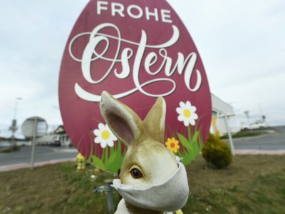 Une effigie de lapin portant un masque près d'une sculpture d'oeuf marquée Joyeuses Pâques sur un rond-point à Deutsckkreutz le 30 mars 2020 - Robert JAEGER [APA/AFP]