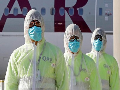 Des employés de Qatar Aviation Services (QAS) en tenues de protection sur le tarmac de Doha, le 1er avril 2020. - KARIM JAAFAR [AFP]