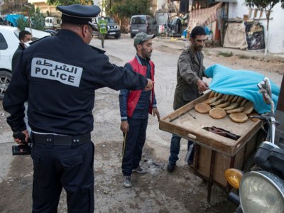 Un policier ordonne à un vendeur de pain de remballer sa marchandise et de rentrer chez lui, le 27 mars 2020 à Rabat pendant l'épidémie de coronavirus - FADEL SENNA [AFP/Archives]