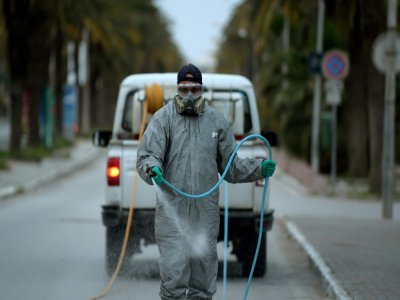 Un employé municipal désinfecte une rue pendant l'épidémie de coronavirus, le 1er avril 2020 à Tunis - FETHI BELAID [AFP]