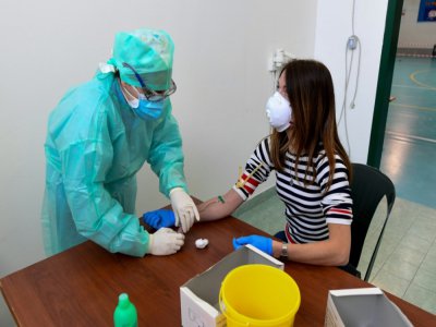 Un membre du personnel soignant prélève un échantillon sanguin auprès d'une habitante pour détecter la présence du Covid-19 à Robbio, dans le nord de l'Italie, le 4 avril 2020 - Miguel MEDINA [AFP]