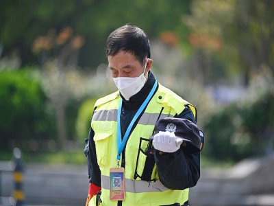 Un policier se fige lors des 3 minutes de silence en mémoire des morts du Covid-19, le 4 avril 2020 à Wuhan - HECTOR RETAMAL [AFP]