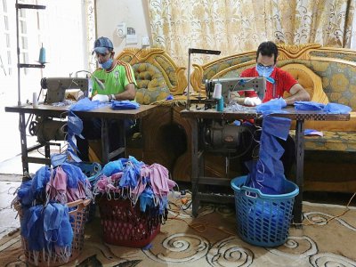 Asaad al-Saadi (g) travaille chez lui à Bagdad, le 3 avril 2020   avec son frère Mohammed après avoir transformé une chambre de la maison en un atelier de fabrication de masques de protection - SABAH ARAR [AFP]