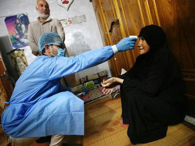 Un médecin irakien vérifie la température d'une femme à Sadr City, dans la banlieue de Bagdad, le 2 avril 2020, dans le cadre des mesures prises par les autorités contre la propagation du nouveau coronavirus - AHMAD AL-RUBAYE [AFP]