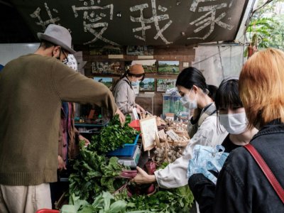 Mandy Tang (centre D), à la tête d'un groupe de pression soutenant les producteurs hongkongais, achète des betteraves produites localement à la ferme communautaire de Mapopo, le 18 mars 2020 à Hong Kong - ANTHONY WALLACE [AFP]