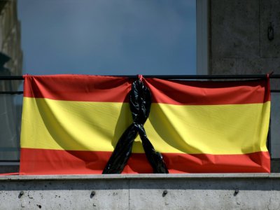 Le drapeau espagnol orné d'un ruban noir, pour les malades et les morts dûs au Covid-19, sur un balcon à Madrid le 8 avril 2020 - Gabriel BOUYS [AFP]