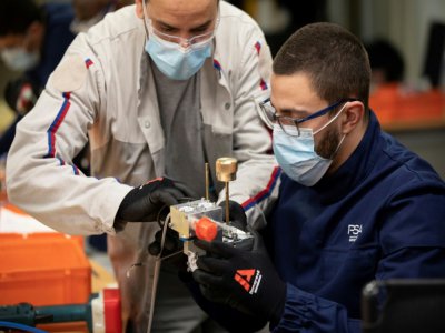 Des employés du groupe automobile PSA assemblent les pièces d'un respirateur médical, le 15 avril 2020 à l'usine de Poissy, au nord-ouest de Paris - Thomas SAMSON [AFP]
