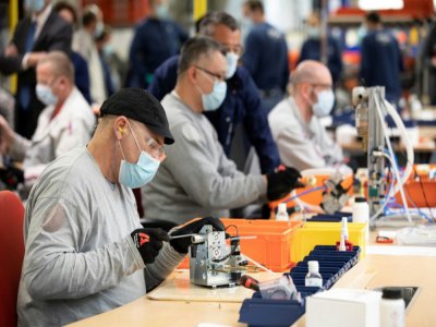 Des employés du groupe automobile PSA assemblent les pièces de respirateurs médicaux, le 15 avril 2020 à l'usine de Poissy, au nord-ouest de Paris - Thomas SAMSON [AFP]