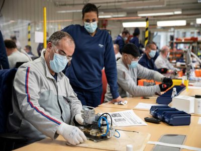 Des employés du groupe automobile PSA assemblent les pièces de respirateurs médicaux, le 15 avril 2020 à l'usine de Poissy, au nord-ouest de Paris - Thomas SAMSON [AFP]