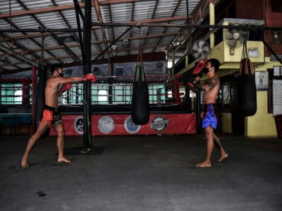Deux boxeurs professionnels, Pongpisarn Sunyong (à gauche) et Sarawut Prohmsut, à l'entraînement avec un masque et en respectant la distanciation sociale dans une salle de muay thaï de Bangkok le 9 avril 2020 - Lillian SUWANRUMPHA [AFP]