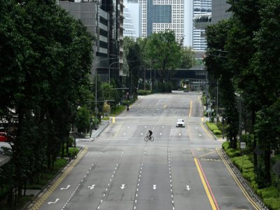 Un cycliste traverse une rue calme du quartier central des affaires de Singapour le 7 avril 2020 - Roslan RAHMAN [AFP/Archives]