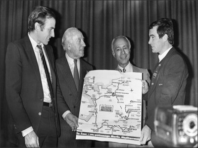 Jacques Goddet avec son associé Félix Lévitan et les cyclistes Joop Zoetemelk et Bernard Hinault le 24 octobre 1980 à Paris lors de la présentation de la carte du Tour 1981 - STF [AFP/Archives]