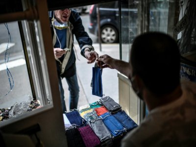 Une boutique de retouches vend des masques en tissu de sa fabrication, le 28 avril 2020 à Paris - STEPHANE DE SAKUTIN [AFP]