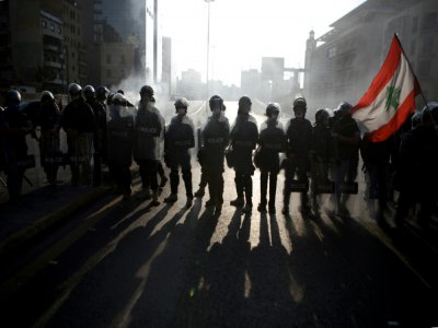 Des manifestants libanais brandissent le drapeau national devant les forces anti-émeutes à Beyrouth, le 28 avril 2020 - PATRICK BAZ [AFP]