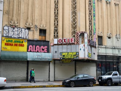 deux personnes passent devant la devanture de magasins fermés dans le centre de Los Angeles le 30 avril 2020 - Robyn Beck [AFP]