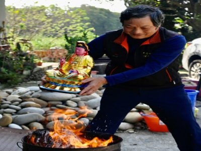 Le sculpteur Lin Hsin-lai tient la statue d'un dieu taoiste au-dessus d'un feu lors d'une cérémonie de bénédiction dans son atelier de Taoyuan, dans le nord de Taïwan, le 17 mars 2020 - Sam Yeh [AFP]