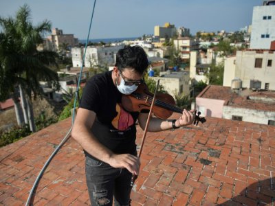 William Roblejo joue du violon sur le toit de sa maison, le 15 avril 2020 à La Havane, à Cuba - YAMIL LAGE [AFP]