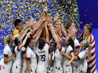 L'équipe de football féminine américaine brandit la Coupe du monde qu'elle vient de remporter, près de Lyon (France) le 7 juillet 2019 - Jean-Philippe KSIAZEK [AFP/Archives]