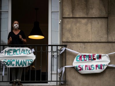 Une femme applaudit les soignants depuis le balcon de son appartement à Saint-Mandé, en banlieue parisienne, le 4 mai 2020  à20h - Martin BUREAU [AFP]