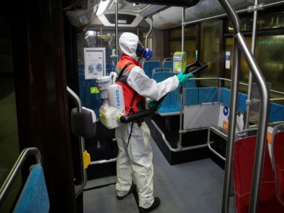 Un salarié d'une entreprise de nettoyage désinfecte un bus de la RATP, à Paris le 5 mai 2020 - Thomas SAMSON [AFP]